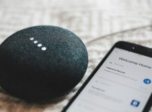 Turned-on charcoal Google Home Mini and smartphone