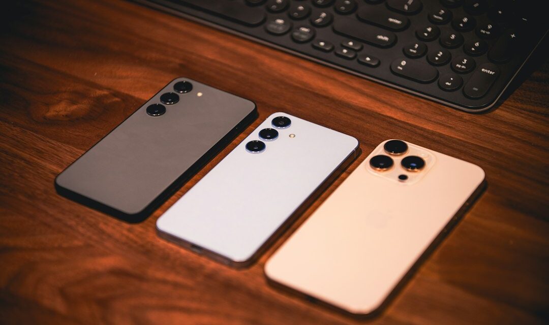 Three smartphones are on a wooden surface