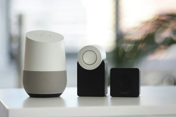 White and gray Google smart speaker and two black speakers
