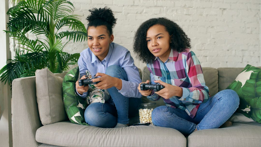Two young women playing video games on a couch