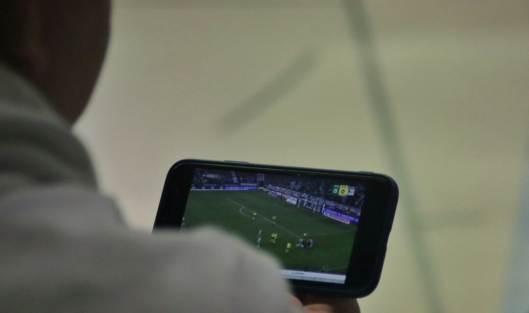 A man is playing a soccer game on his phone