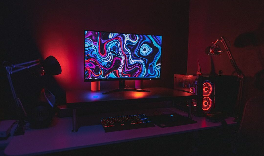 Black flat screen computer monitor turned on near black computer keyboard