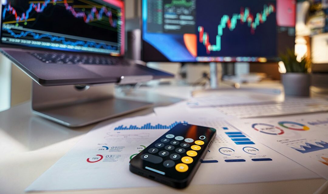 Smartphone calculator on desk with financial charts behind