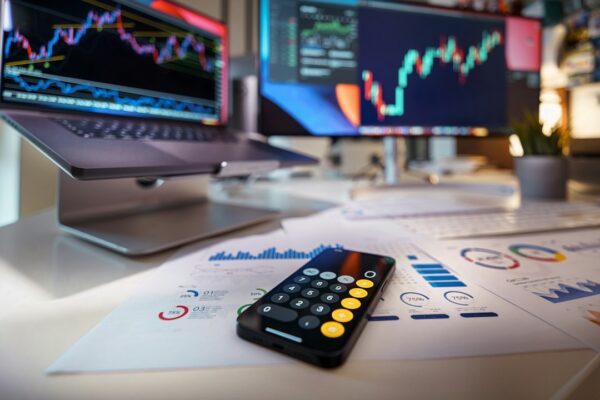 Smartphone calculator on desk with financial charts behind