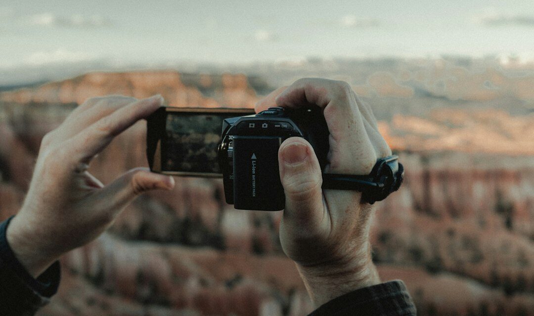 Person holding black smartphone taking photo of brown field during daytime