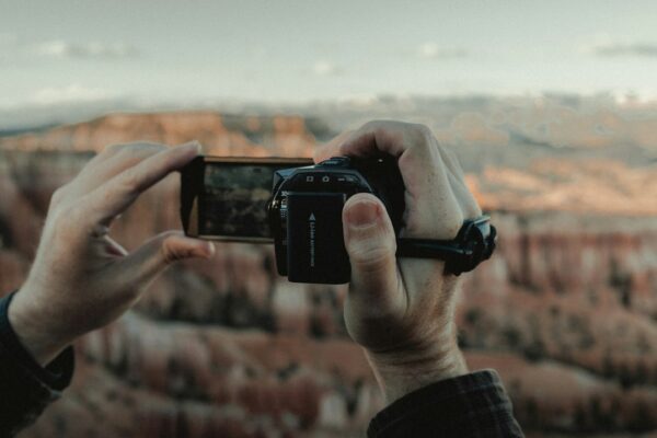 Person holding black smartphone taking photo of brown field during daytime