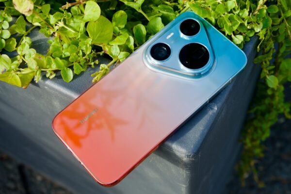 A smartphone with a gradient orange and blue back resting on a grey planter