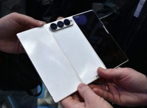 Hands hold a white foldable smartphone with three cameras