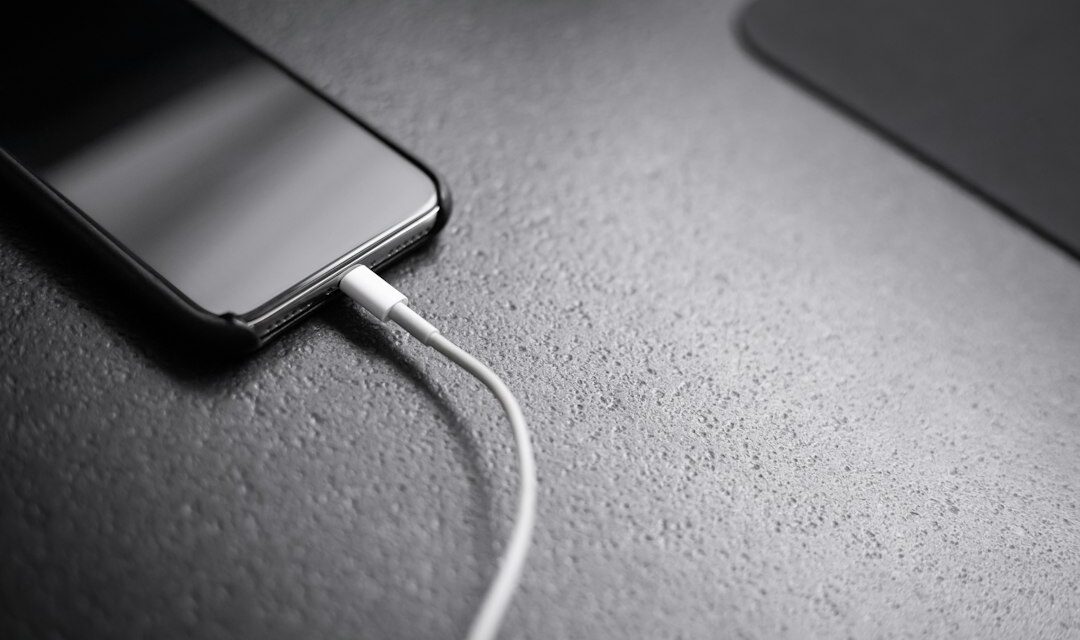 Black smartphone with charger cord connected