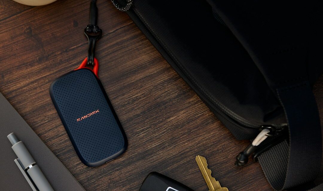 Portable ssd, keys, and pen next to a black bag