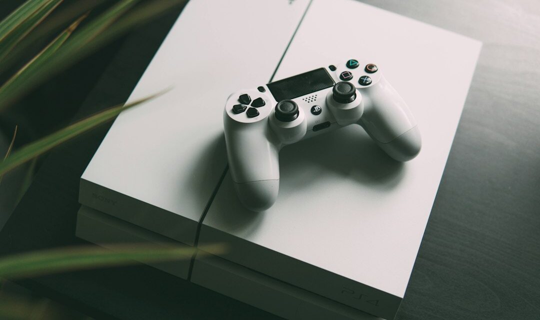 Selective focus photography of white Sony PS4 console with wireless controller