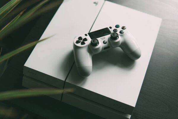 Selective focus photography of white Sony PS4 console with wireless controller