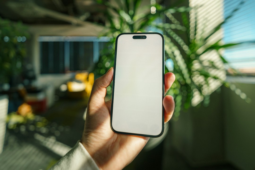 Hand holding a smartphone with a blank screen