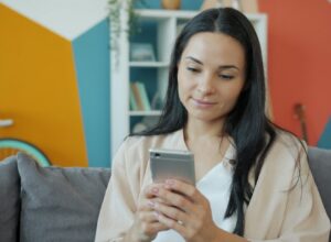A woman looking at her smartphone on a couch