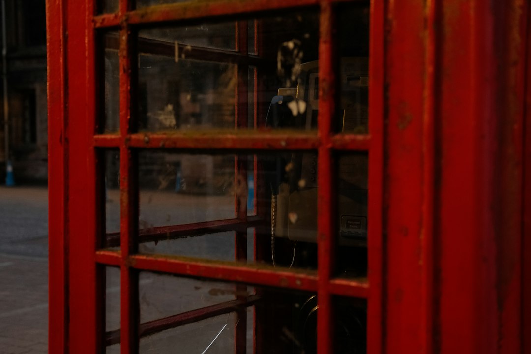 A red telephone booth sitting on the side of a road