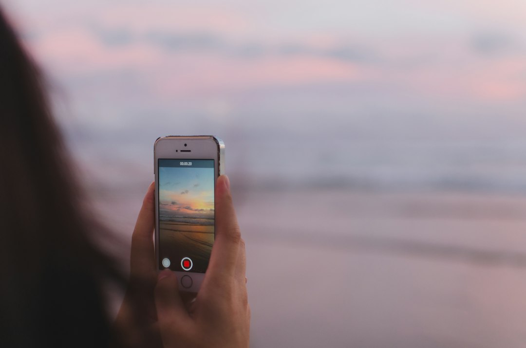 Person taking a photo of of open sea and sunset