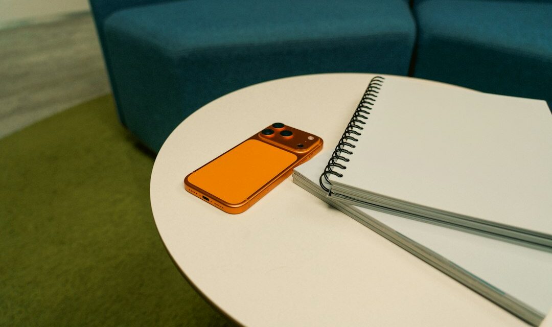 Orange phone and notebook on a white table