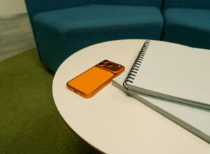 Orange phone and notebook on a white table