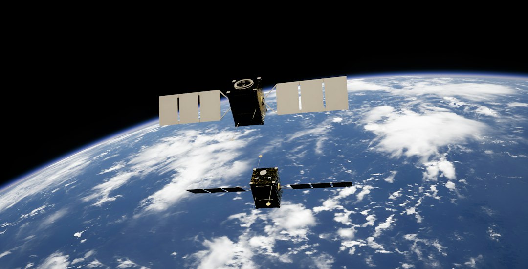 Two satellites with solar panels orbiting above the blue Earth with white clouds