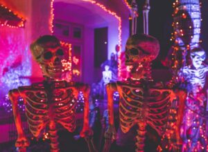 Two skeleton near white concrete building with string lights at daytime