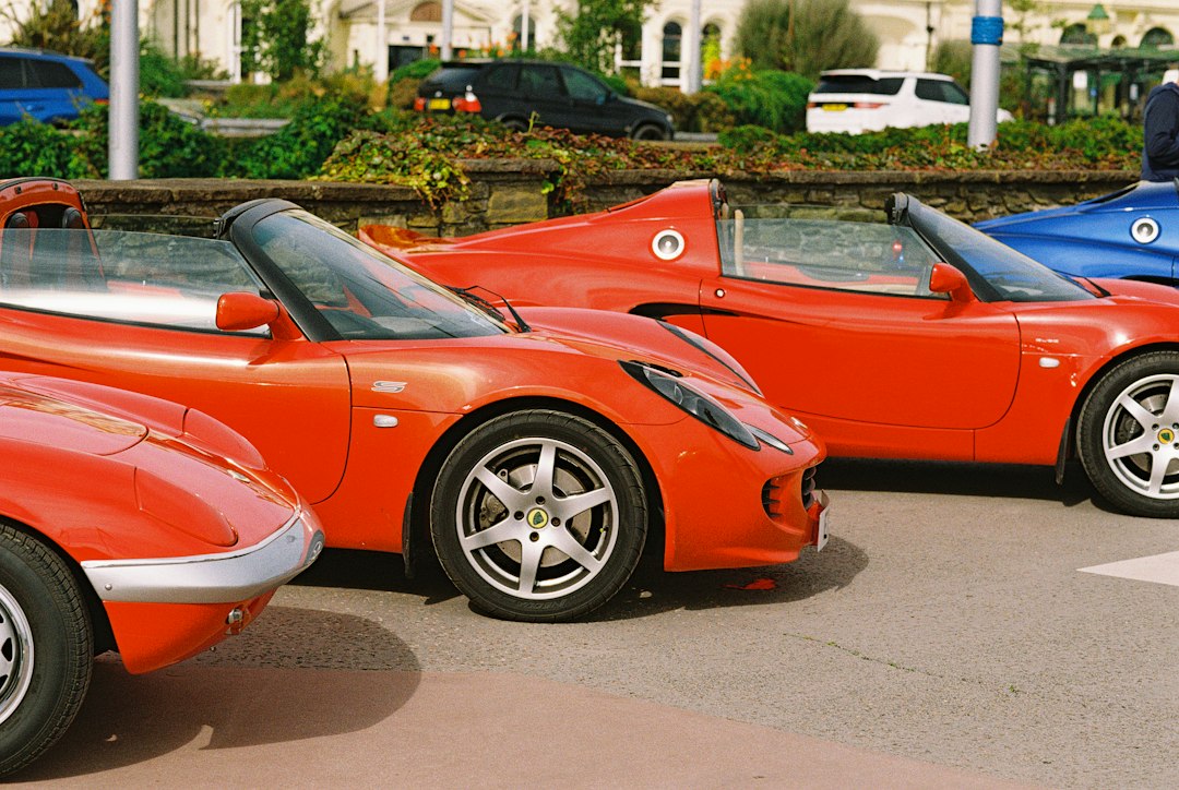 Three red Lotus sports cars parked in a row on a paved lot