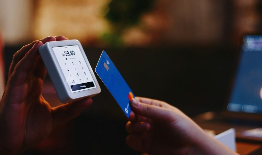 A person holding a credit card and a cell phone