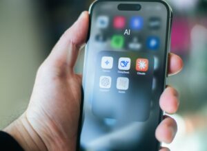 A hand holds a smartphone with various apps