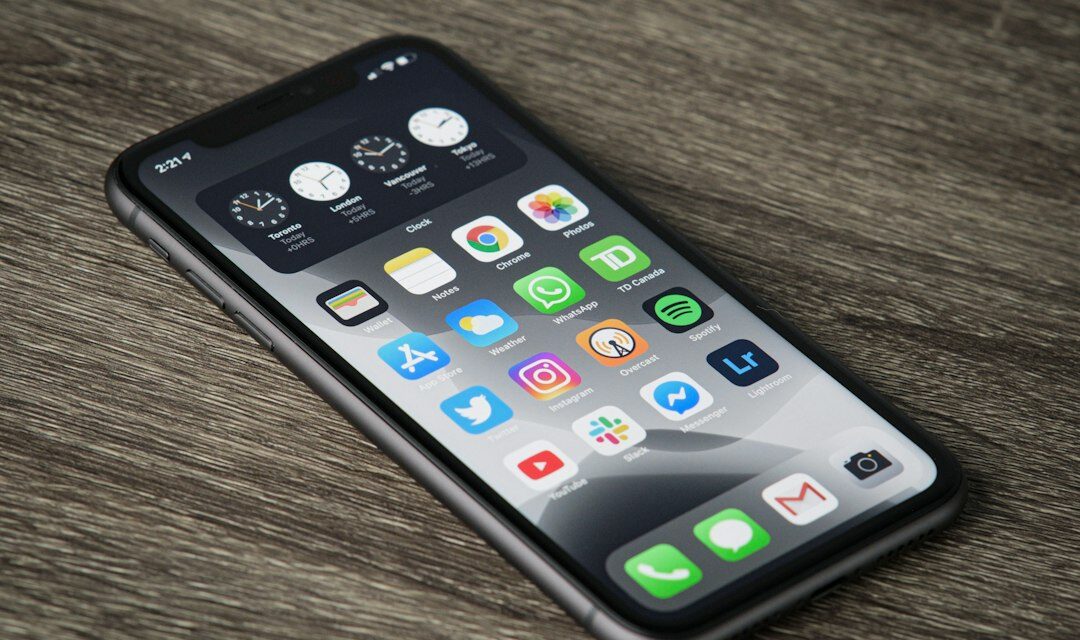 A smartphone with a home screen full of app icons on a wooden surface
