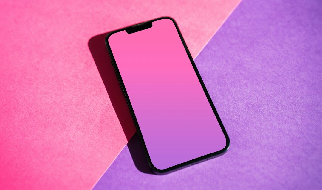 A pink and purple phone sitting on top of a purple and pink background