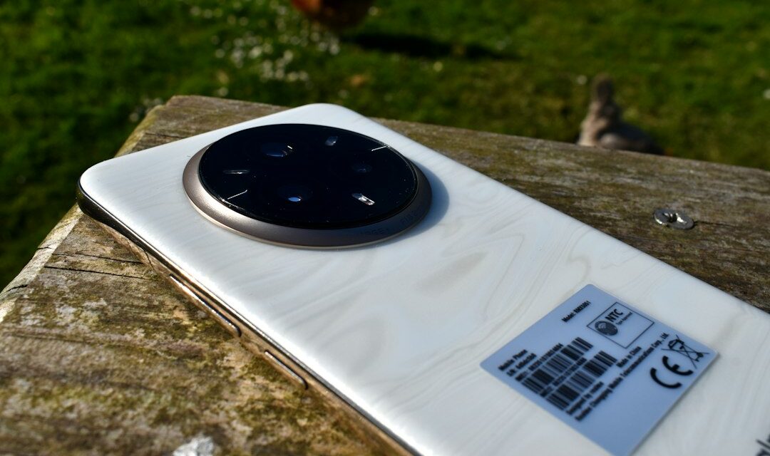 White smartphone with circular camera on wooden surface outdoors