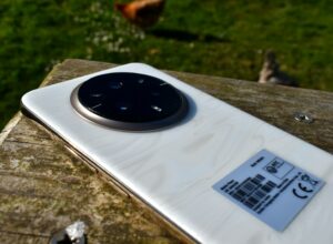 White smartphone with circular camera on wooden surface outdoors